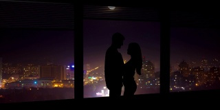 这对情侣站在窗前，背景是夜晚的城市。时间流逝