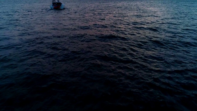 孤独的游艇，双体帆船在夕阳西下的海面上航行。