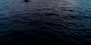 孤独的游艇，双体帆船在夕阳西下的海面上航行。