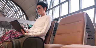 一名亚洲女性在机场候机厅使用平板电脑