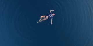 鸟瞰图一个迷人的女孩在黑色t恤漂浮在惊人的蓝色水域