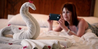女孩用手机拍了一张用毛巾做的天鹅的照片