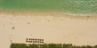 阳光明媚的三亚著名的大东海拥挤的海滩空中全景4k海南中国