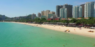 阳光明媚的三亚著名的大东海拥挤的海滩空中海滨全景4k海南中国