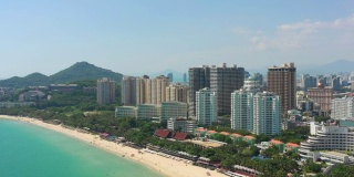 阳光明媚的三亚著名的大东海拥挤的海滩湾空中全景4k海南中国