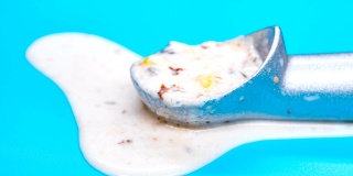 侧视图栗子和红豆冰淇淋球融化时间在勺子上在蓝色的背景