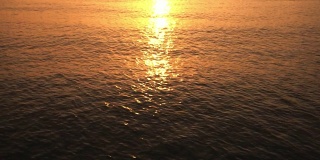 海浪在日出与金色的光在地平线热带;在户外放松的假期。夏天，海深浅黄水。