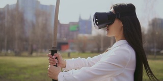 中国女孩戴着虚拟现实眼镜看剑。风吹在头发上。