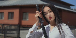 亚洲美女把华丽的剑从鞘中抽出，崇拜地看着它。
