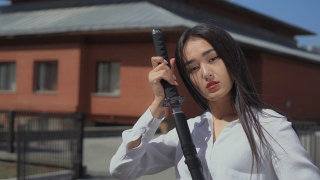 亚洲美女把华丽的剑从鞘中抽出，崇拜地看着它。视频素材模板下载
