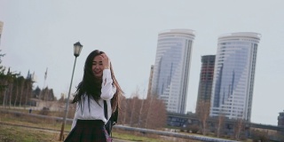 笑着的亚洲女孩穿着漂亮的制服在放学后沿着小巷跳
