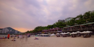 日落三亚著名的大东海拥挤的海滩全景4k时间推移海南岛中国