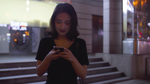 迷人的年轻亚洲女人在城市里使用手机的慢镜头