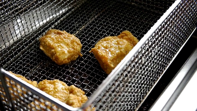 烹饪油炸面包屑鸡。在热油炸锅里炸鸡块的特写