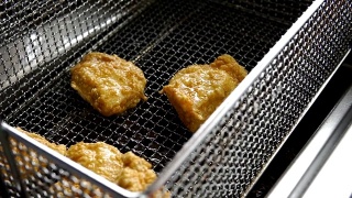 烹饪油炸面包屑鸡。在热油炸锅里炸鸡块的特写视频素材模板下载