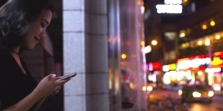 迷人的年轻亚洲女人在城市里使用手机的慢镜头