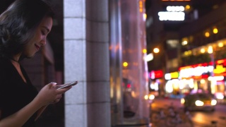 迷人的年轻亚洲女人在城市里使用手机的慢镜头视频素材模板下载