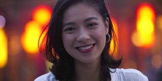 夏城的夜晚，一名年轻的亚洲女子对着镜头微笑，4k美元