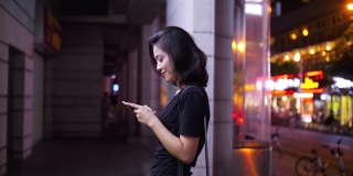 侧面的可爱的年轻亚洲女人使用手机在街上