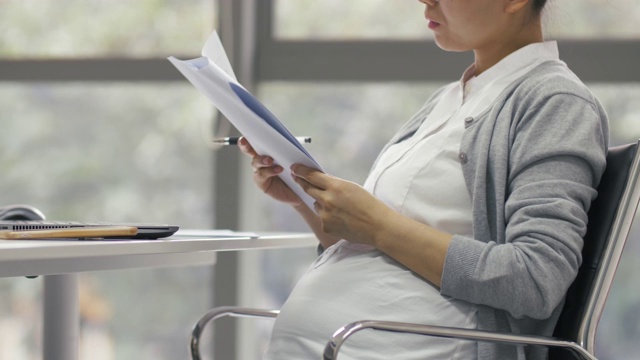 中国怀孕女商人在办公室工作的侧面图