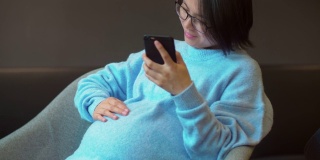 一名中国孕妇正在坐着使用手机