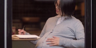 中国孕妇正在咖啡馆里写作