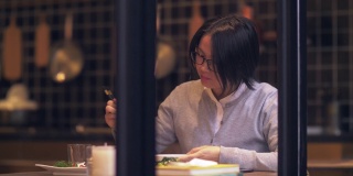 美丽的中国女人正在用手机吃饭