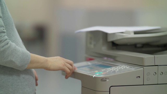 中国怀孕的办公室妇女在用复印机