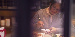 美丽的中国女人在餐厅使用手机用餐