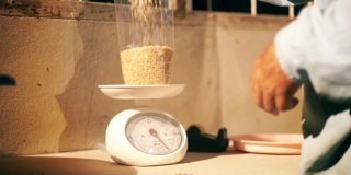 在家中，老农双手用公斤重计称量糙米。