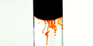 视频中红色食物色墨水血雨从油中滴入透明试管中的水中