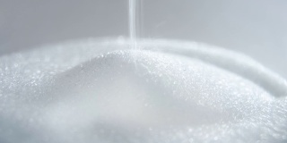 一堆糖、盐或白色颗粒状的小晶体落下来形成一个金字塔。