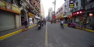 中国人骑着摩托车在拥挤的街道上行走。