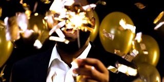 快乐的非裔美国男人在飘落的五彩纸屑下挥舞着孟加拉灯，派对