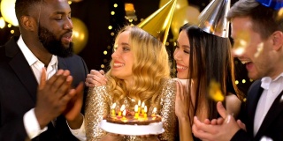快乐的女性和密友一起享受生日，吹灭蛋糕蜡烛