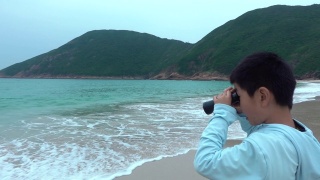 顽皮的男孩用双筒望远镜看海滩视频素材模板下载