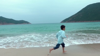 顽皮的男孩在海滩上开始和奔跑视频素材模板下载