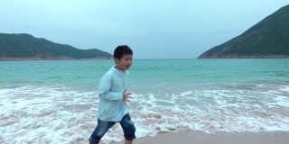 顽皮的男孩害怕海滩上的波浪