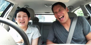 成熟的亚洲夫妇在车里谈笑风生。亚洲的中年朋友喜欢在开车的时候交谈