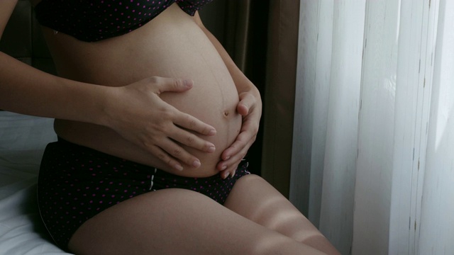 孕妇抚摸并展示她的腹部