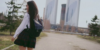 微笑的日本女学生在短裙跳沿着街道课后。