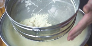 厨师用筛子筛面粉，以便烘烤。面包房用手将面粉通过筛子倒入碗中。准备烘焙原料。烹饪食物的概念