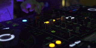 夜总会里的DJ控制音乐控制台和五彩缤纷的灯光。在迪斯科舞会上，DJ在音响上播放音乐。彩色照明的唱片骑师面板和混合甲板