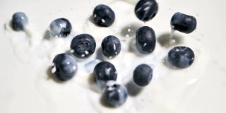 蓝莓葡萄落在牛奶表面的SLO MO镜头。