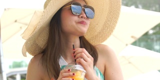 在海滩上喝橙汁的美女。