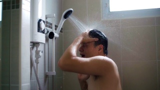 年轻的亚洲男人在浴室里用慢动作洗淋浴。视频素材模板下载
