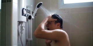 年轻的亚洲男人在浴室里用慢动作洗淋浴。