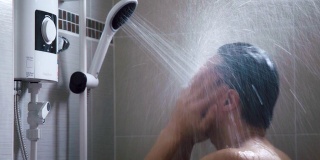 年轻的亚洲男人在浴室里用淋浴洗澡，充满新鲜感。