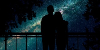 这对情侣站在树旁，映衬着繁星点点的天空。时间流逝