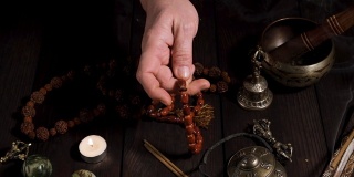 男手捧着一串棕色的念珠石，在桌子上冥想和替代药物的物品